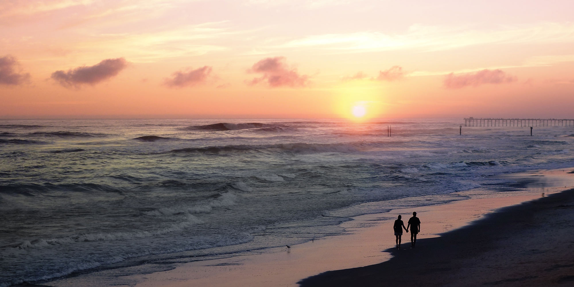 Couple holding hands on a beach at sunset