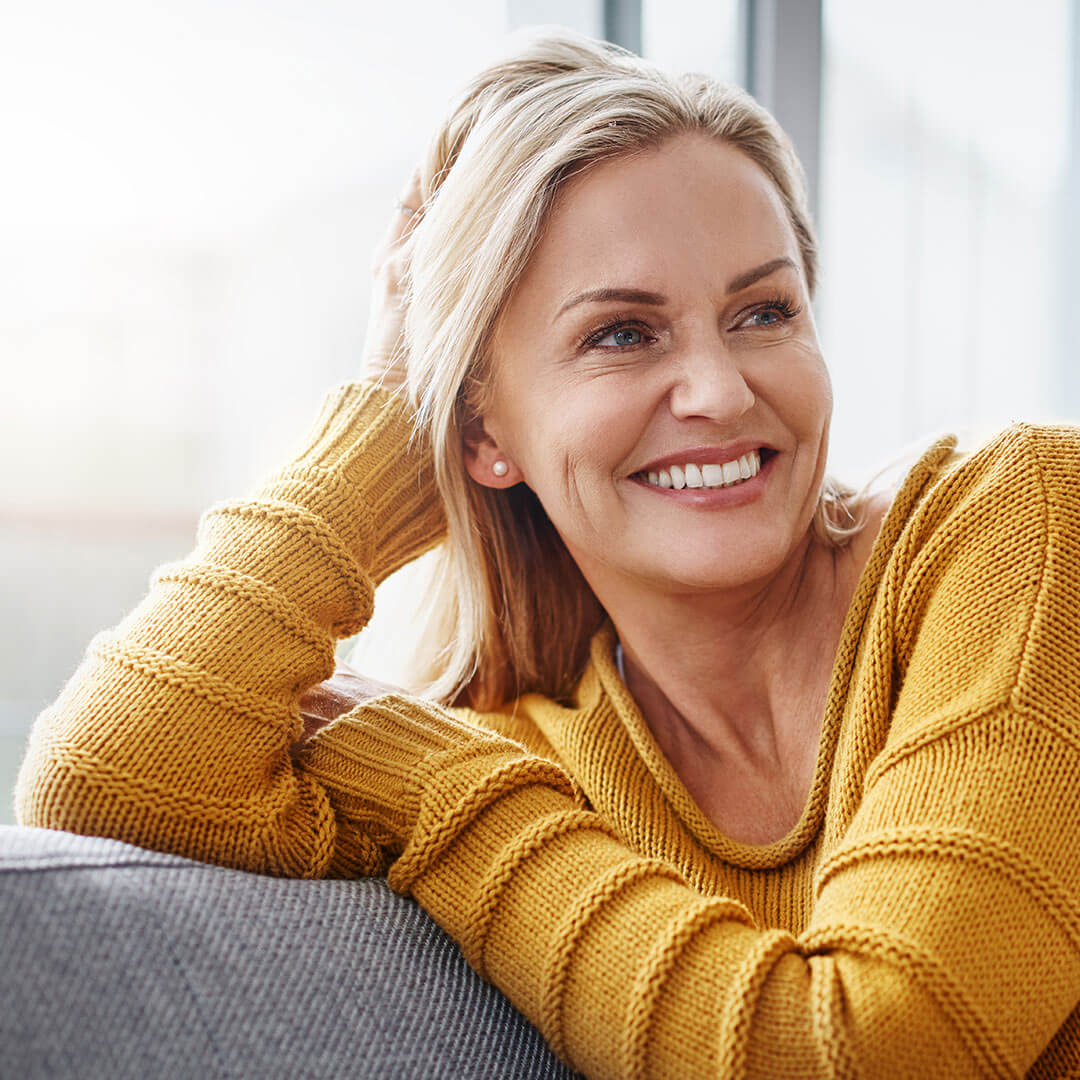 Woman smiling on a couch - Crowns and bridges in Sneads Ferry NC