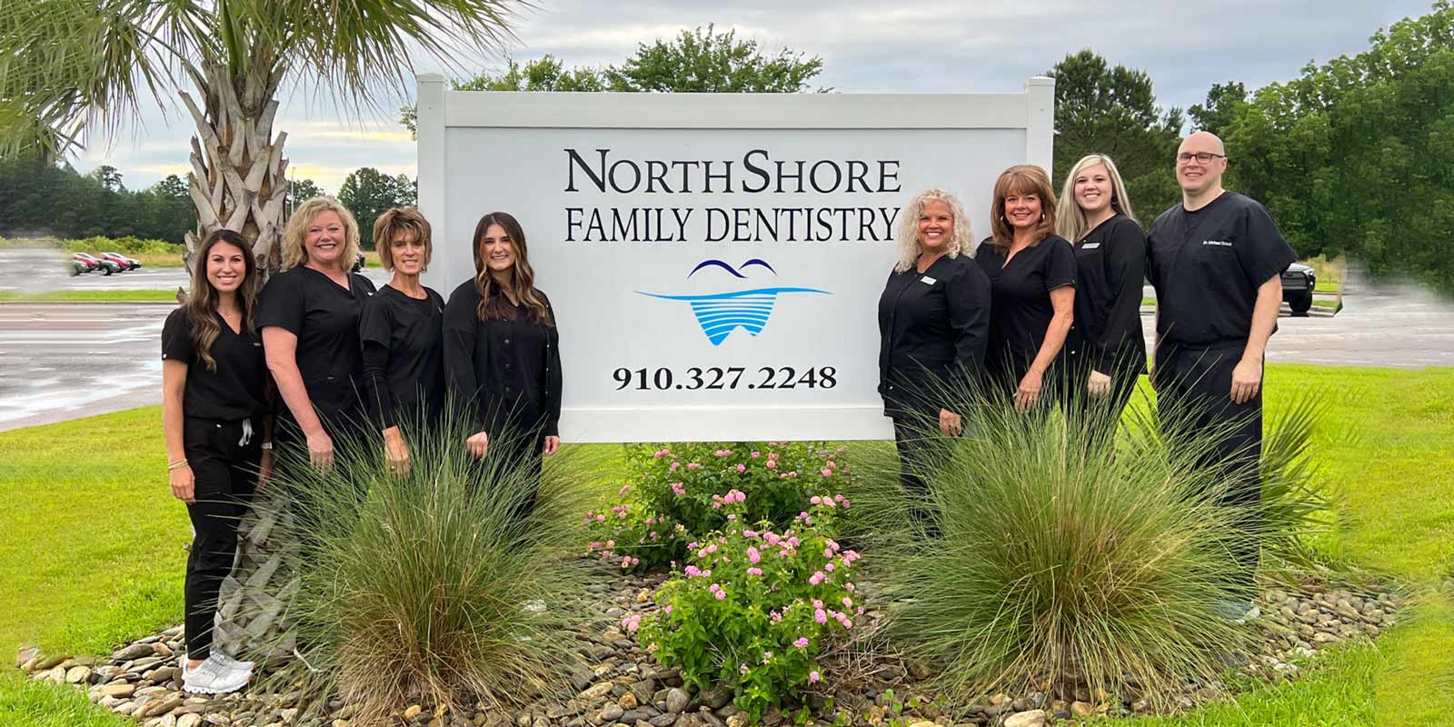 dr michael schut and his team smiling in front of sign